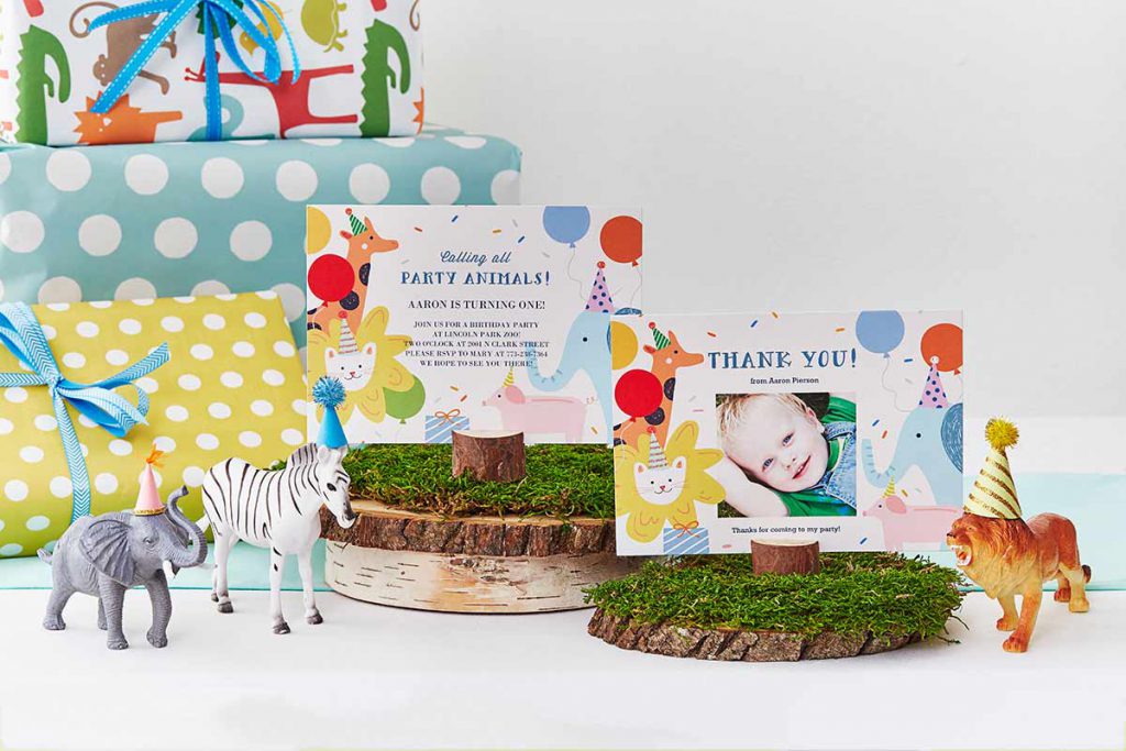 Party animal photo invites that say "Calling all party animals!" and a photo thank you card on a table decorated with birthday gifts and plastic zoo animals