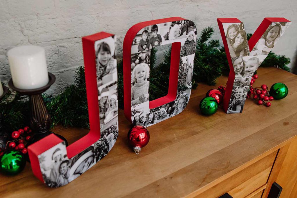 Completed DIY Joy photo block letters displayed on a credenza with holiday decorations