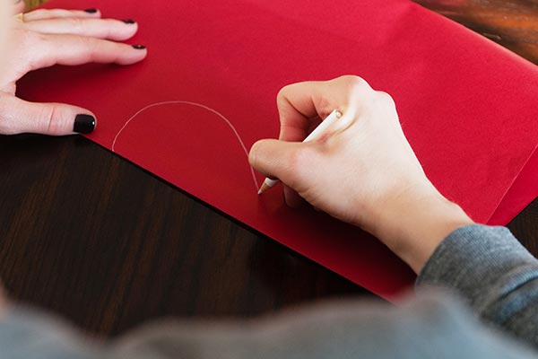Drawing half a heart on a folded piece of red construction paper