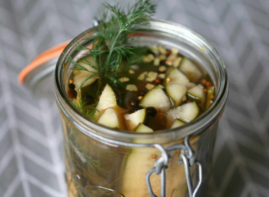 Homemade dill pickles in a glass jar container with the lid open