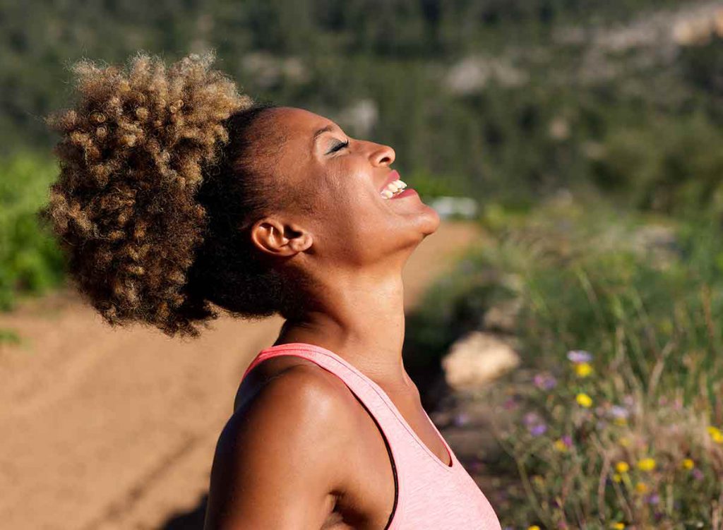 Woman standing outside in the sun while taking a break from running