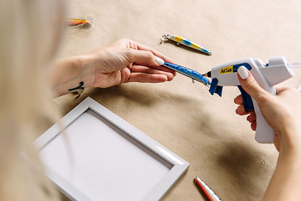 Adding fishing lures to the frame with a low-heat glue gun.