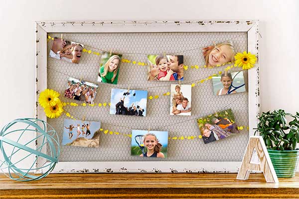 Simple wood frame with 4x6 prints clipped to chicken wire in the opening. Decorated with yellow garland.