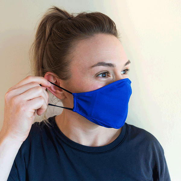 Woman wearing face mask, pulling the strap over her ear.